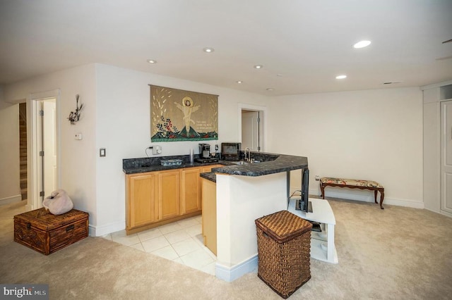 kitchen with light brown cabinetry, sink, and light carpet