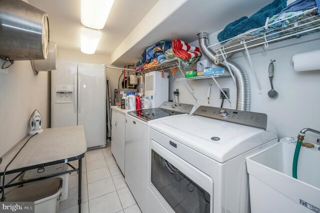 laundry area with light tile patterned flooring, independent washer and dryer, and sink