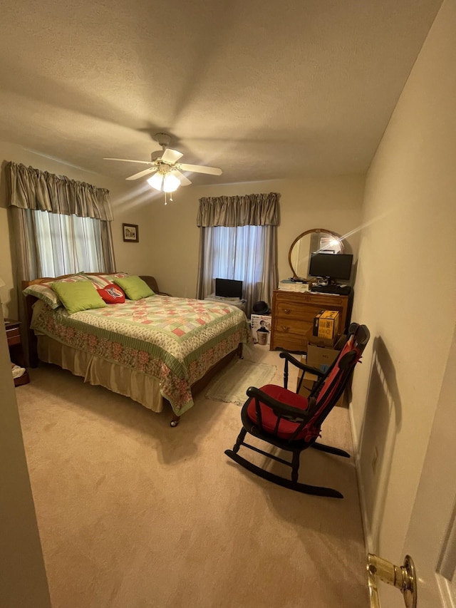 carpeted bedroom featuring ceiling fan and a textured ceiling