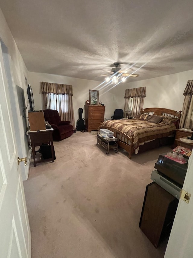 bedroom with ceiling fan, a textured ceiling, and carpet flooring