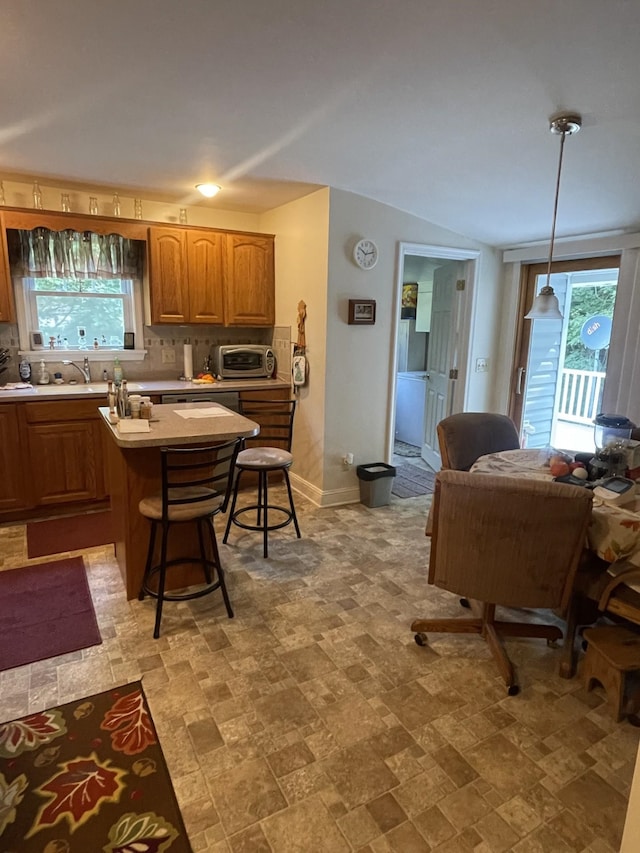 kitchen featuring decorative light fixtures, a breakfast bar, decorative backsplash, and a wealth of natural light