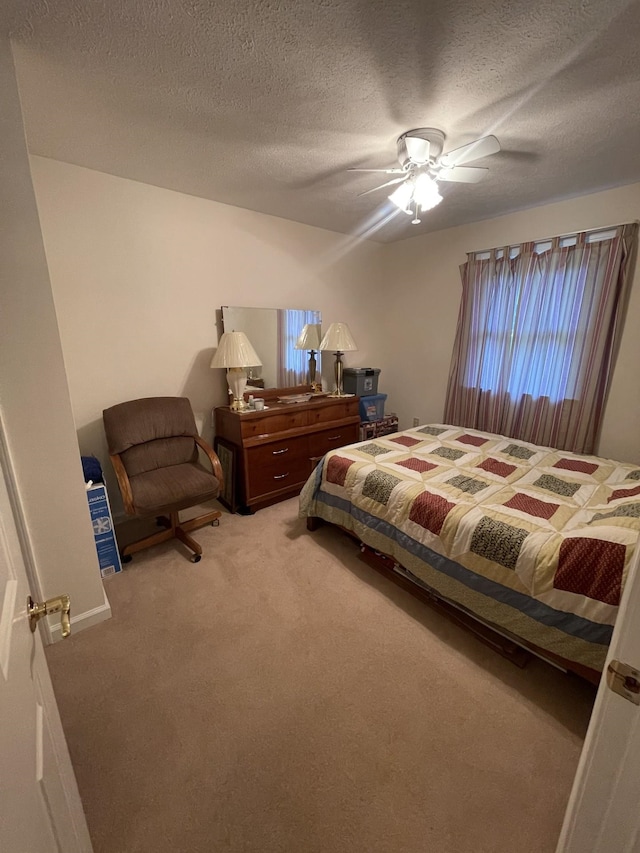 bedroom featuring ceiling fan, light colored carpet, and a textured ceiling