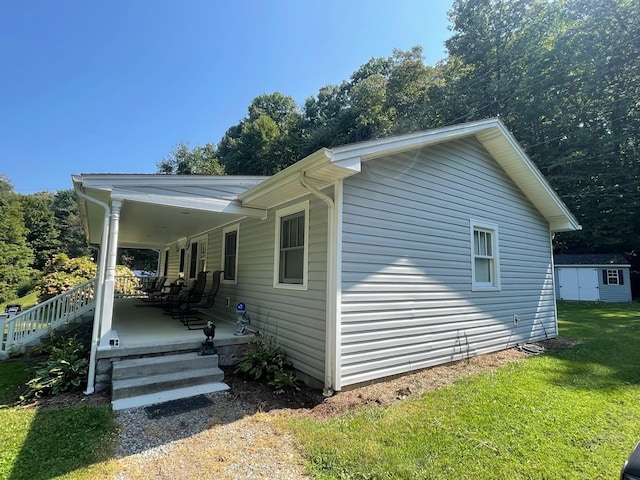 view of property exterior featuring a lawn, a storage unit, and covered porch