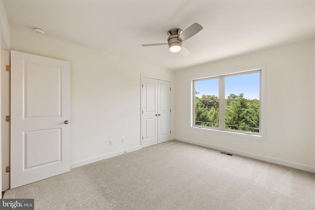 unfurnished bedroom featuring ceiling fan, a closet, and light carpet