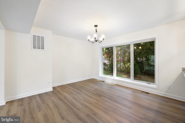 empty room featuring dark hardwood / wood-style flooring and an inviting chandelier