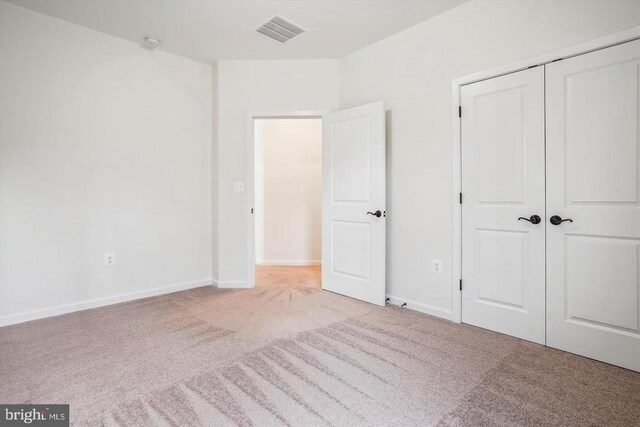 unfurnished bedroom with light carpet and a closet