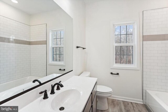 bathroom featuring a healthy amount of sunlight, toilet, wood-type flooring, and vanity