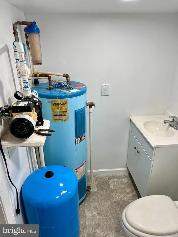 bathroom featuring vanity, water heater, and toilet