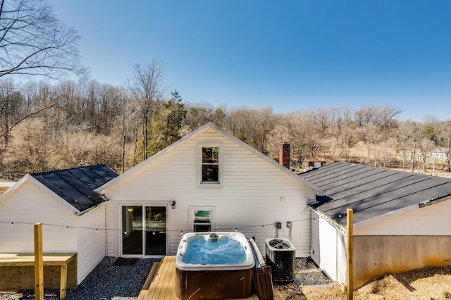 rear view of property with a hot tub, a deck, and central air condition unit