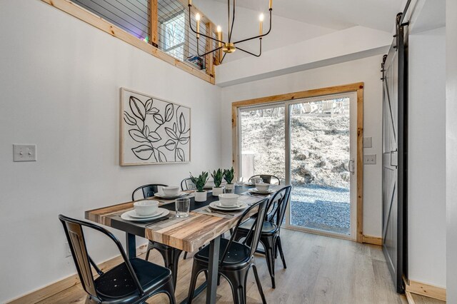 dining room featuring a barn door, an inviting chandelier, and light hardwood / wood-style floors