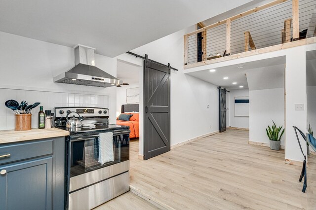 kitchen featuring backsplash, electric range, a barn door, exhaust hood, and light wood-type flooring