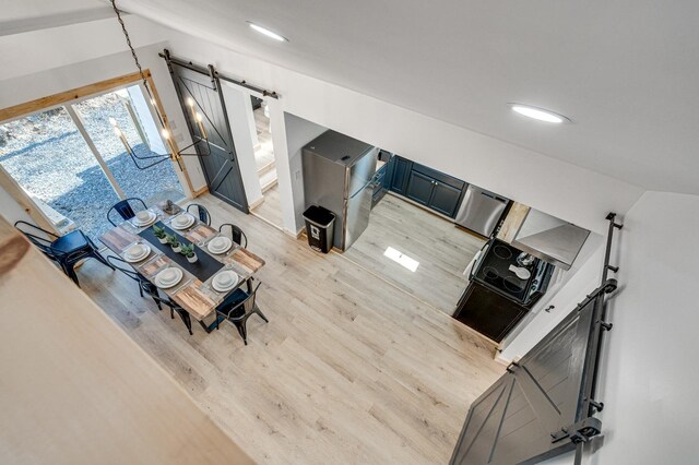 living room featuring a barn door, vaulted ceiling, and light wood-type flooring