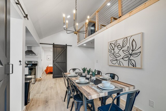 dining room with a towering ceiling, light hardwood / wood-style flooring, a barn door, and a chandelier