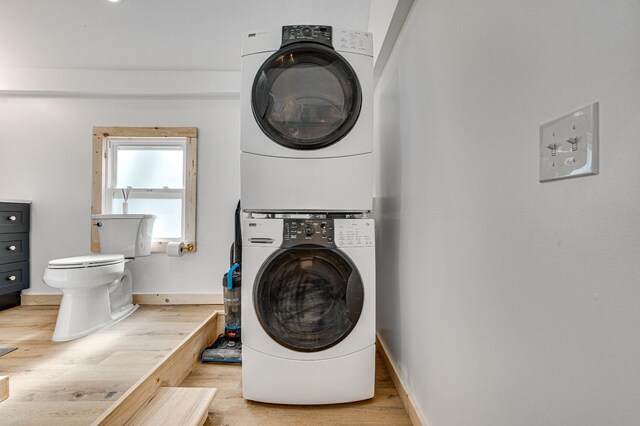 washroom with stacked washing maching and dryer and hardwood / wood-style floors