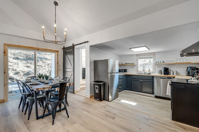 dining room with a barn door, sink, light hardwood / wood-style floors, and plenty of natural light