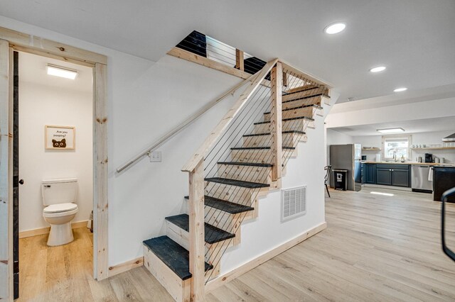 staircase with hardwood / wood-style floors and sink