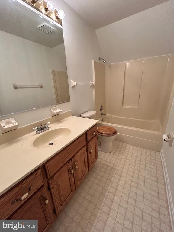 full bathroom with lofted ceiling, shower / washtub combination, toilet, and vanity