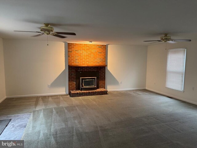 unfurnished living room with a brick fireplace, carpet floors, and ceiling fan