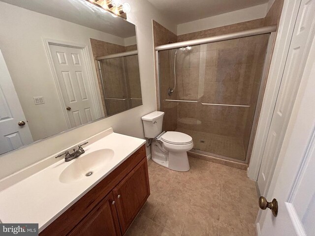 bathroom with vanity, a shower with shower door, and toilet