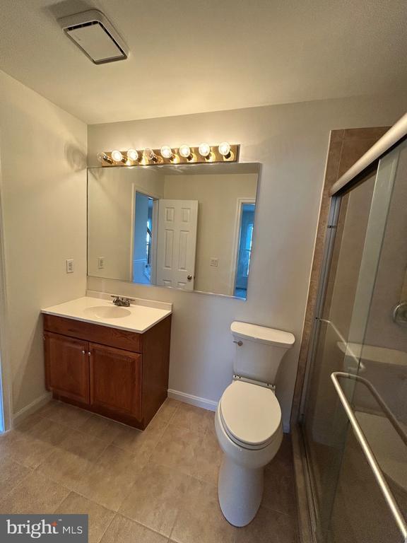 bathroom featuring an enclosed shower, vanity, and toilet