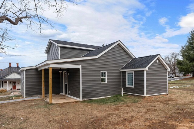 rear view of property featuring roof with shingles and a patio area