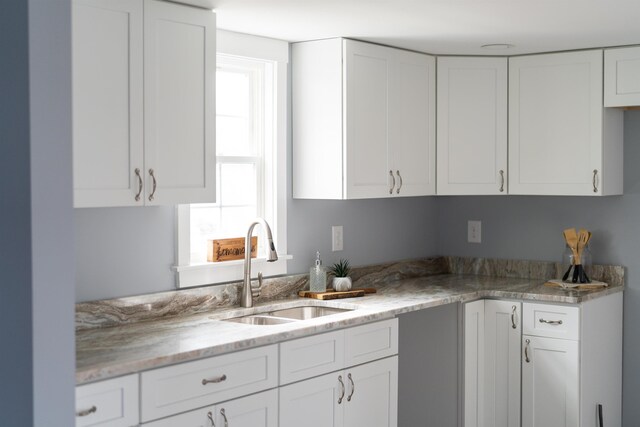 kitchen featuring a wealth of natural light, white cabinets, and a sink