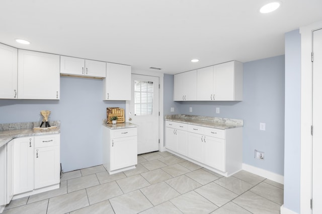 kitchen with light stone countertops, white cabinets, and recessed lighting