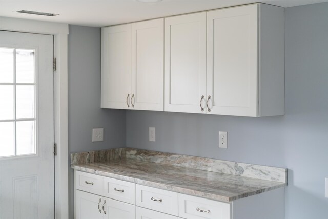 kitchen featuring a wealth of natural light, white cabinets, and light stone countertops