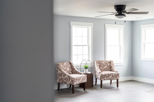 living area with ceiling fan, baseboards, and wood finished floors