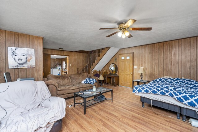 bedroom featuring wooden walls, light wood-style flooring, and a textured ceiling