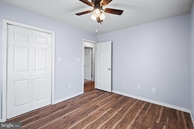 unfurnished bedroom featuring ceiling fan, a closet, and dark hardwood / wood-style flooring