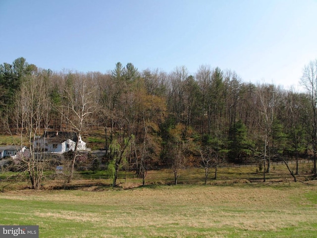 view of yard featuring a forest view and fence