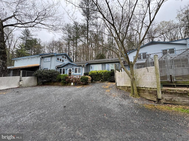 traditional home with gravel driveway and fence