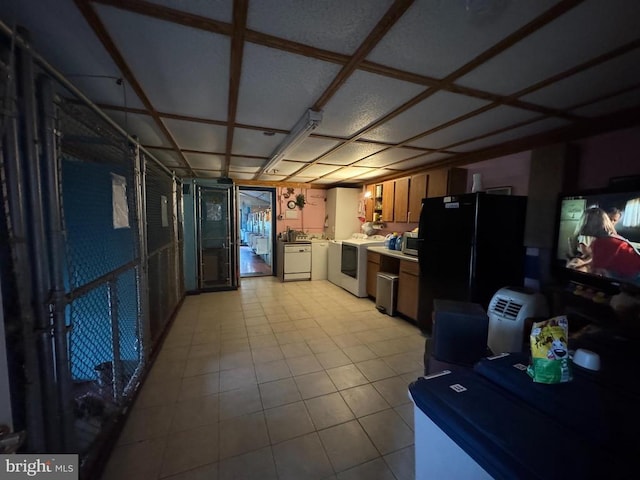 kitchen with range, freestanding refrigerator, stainless steel microwave, light countertops, and washer and clothes dryer