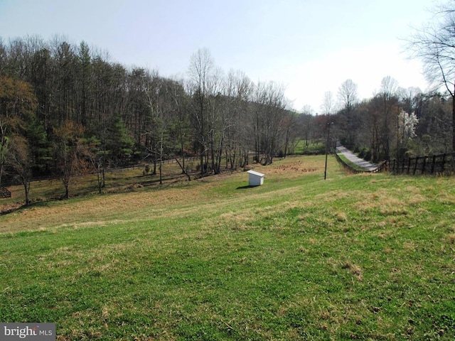 view of yard featuring a rural view, a forest view, and fence
