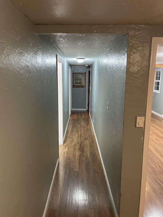 hallway with hardwood / wood-style flooring and a textured ceiling