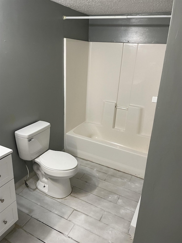 full bathroom with vanity, a textured ceiling, shower / washtub combination, and toilet