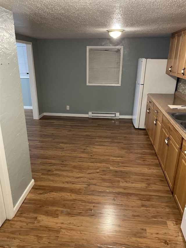 kitchen with sink, a textured ceiling, white refrigerator, dark hardwood / wood-style floors, and a baseboard heating unit