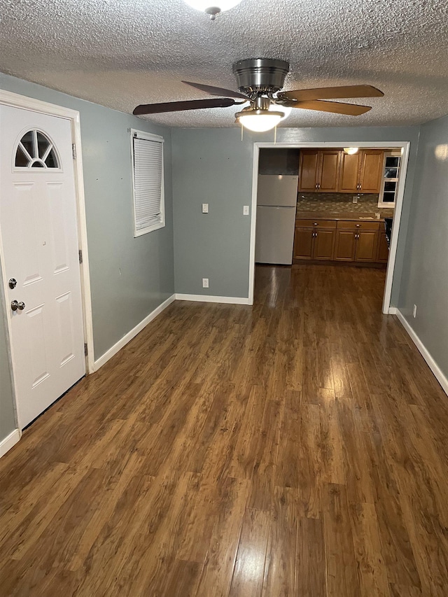 interior space featuring dark hardwood / wood-style flooring, a textured ceiling, and ceiling fan