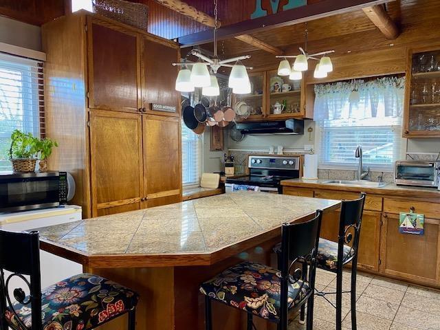 kitchen featuring sink, a center island, appliances with stainless steel finishes, a notable chandelier, and pendant lighting