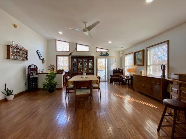 dining space with ceiling fan, wood-type flooring, and vaulted ceiling