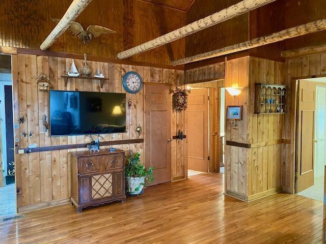 living room featuring hardwood / wood-style flooring, wooden walls, and high vaulted ceiling