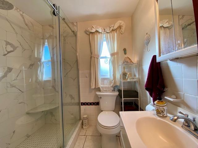 bathroom featuring sink, tile walls, toilet, a shower with door, and tile patterned floors