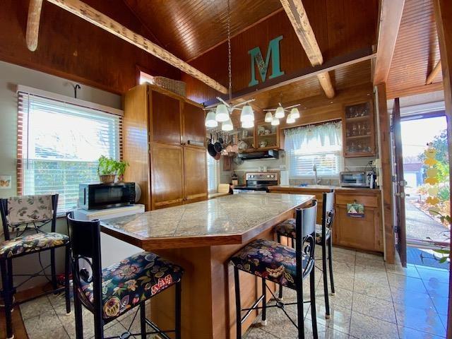 kitchen with sink, extractor fan, a kitchen bar, stainless steel electric stove, and wooden ceiling