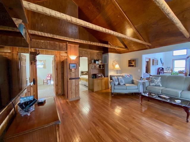 living room with hardwood / wood-style floors, wood ceiling, wooden walls, and high vaulted ceiling