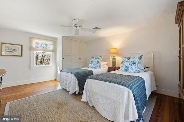 bedroom featuring visible vents, baseboards, wood finished floors, a closet, and a ceiling fan