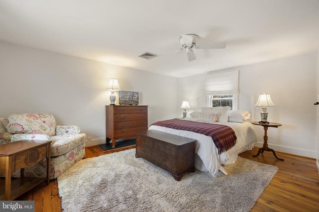 bedroom featuring ceiling fan, wood finished floors, visible vents, and baseboards