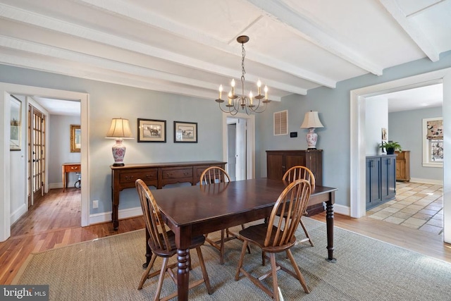 dining space with beam ceiling, a chandelier, light wood-type flooring, and baseboards