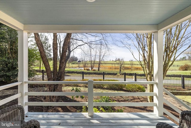 wooden terrace featuring a rural view and fence