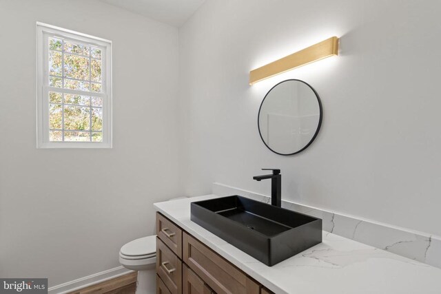 half bath with vanity, toilet, and baseboards
